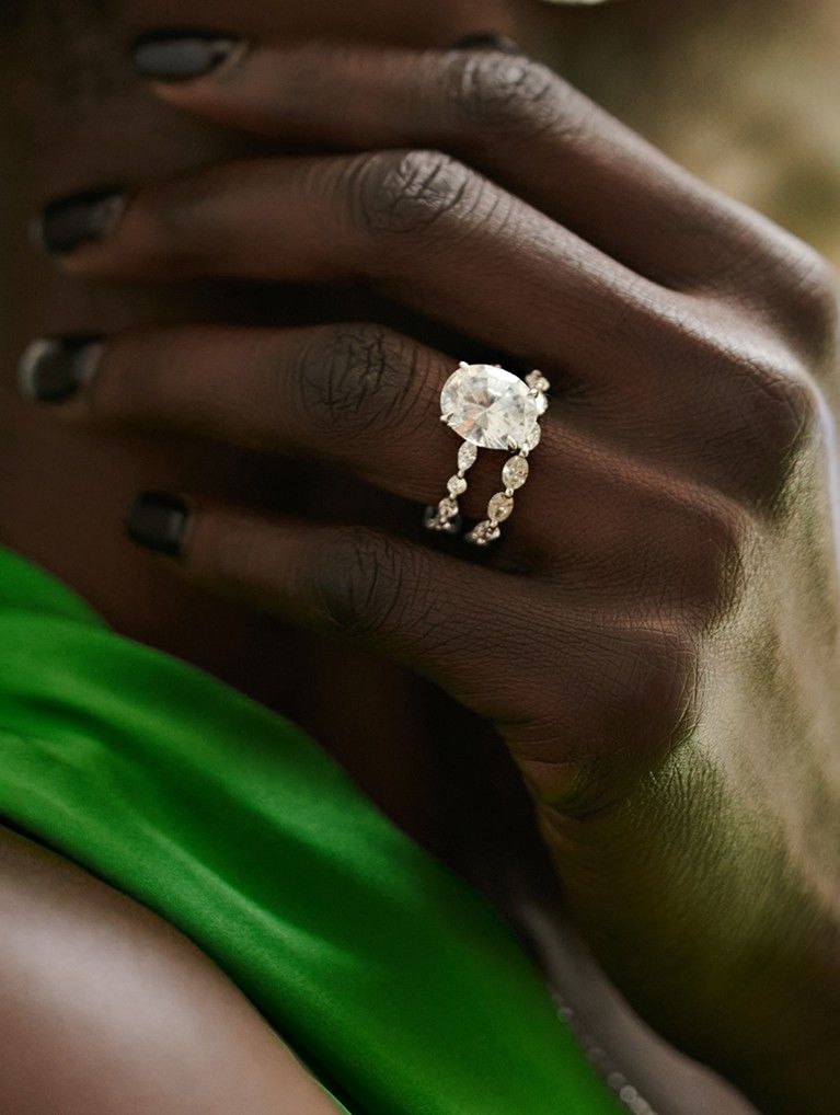 Model wearing diamond engagement ring and wedding ring bridal set.